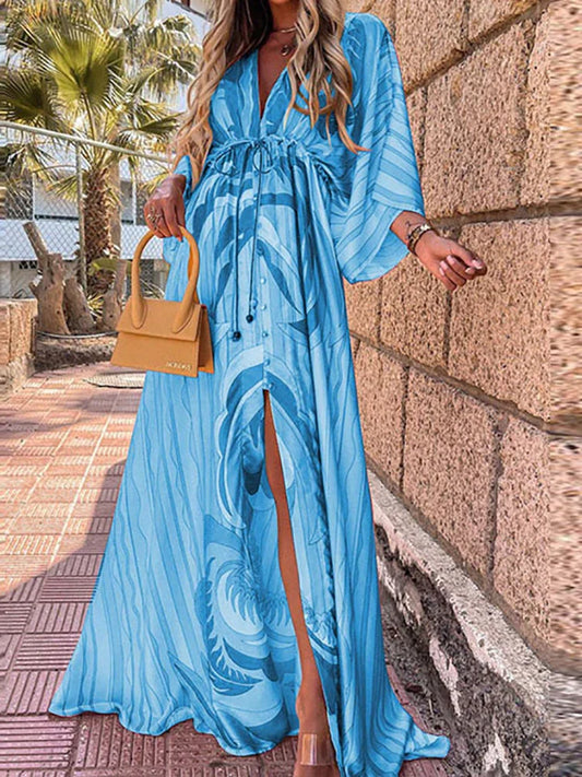 Frau in blauem Maxikleid mit Muster, gelbe Handtasche, Sommermode, draußen, Palmen im Hintergrund.