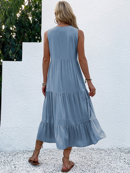 Frau in blauem Sommerkleid aus Baumwolle, Rückansicht, vor weißer Wand, Sandalen, lässig.