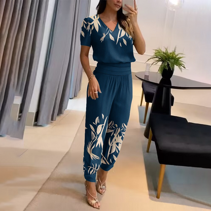 Frau in blauem, gemustertem Jumpsuit im modernen Wohnzimmer, elegantes Design.