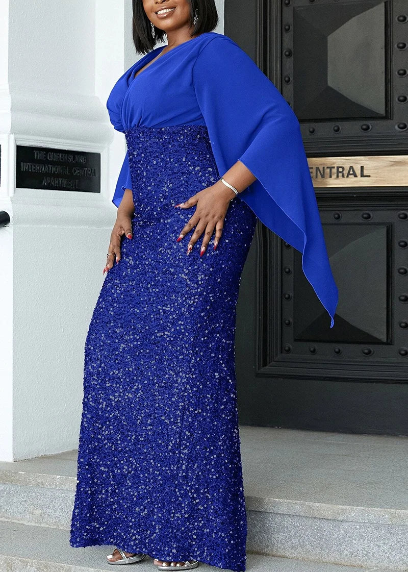 Frau in eleganter, blauer Paillettenkleid mit Umhang, Abendmode, vor schwarzer Tür.
