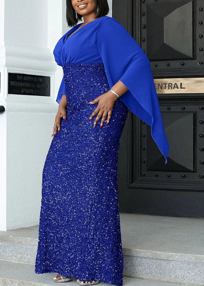 Frau in eleganter, blauer Paillettenkleid mit Umhang, Abendmode, vor schwarzer Tür.