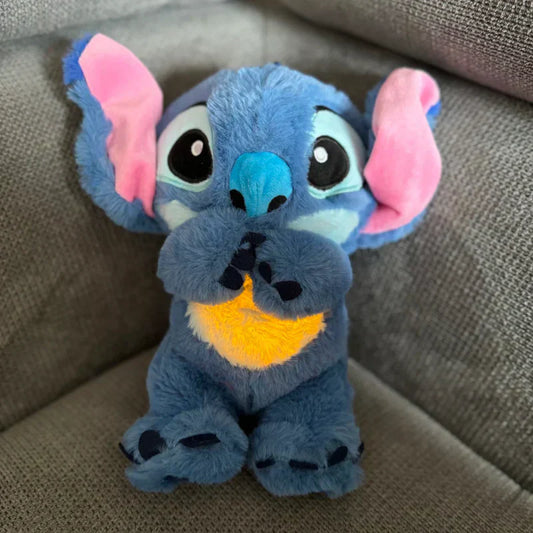 Blaues Plüsch-Stofftier mit großen Ohren, auf grauem Sofa sitzend, Kinder-Spielzeug.