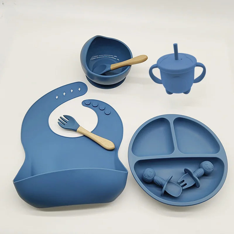Blaues Silikon-Babygeschirr-Set mit Lätzchen, Teller, Schüssel, Becher und Besteck.