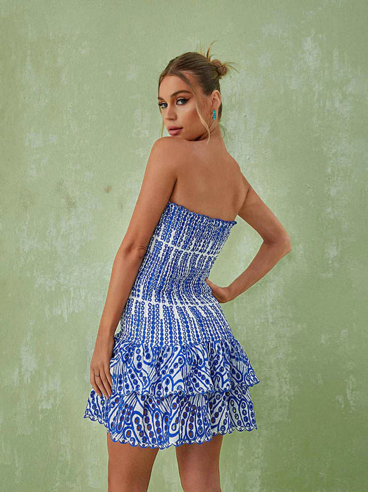 Frau im blauen, trägerlosen Sommerkleid mit Muster vor grünem Hintergrund.