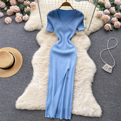 Blaues Strickkleid mit V-Ausschnitt, kurze Ärmel, auf weißem Fell, umgeben von Rosen.