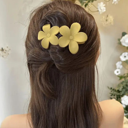Frau mit braunem Haar trägt gelbe Blumen-Haarspangen, elegantes Accessoire, Frisur.