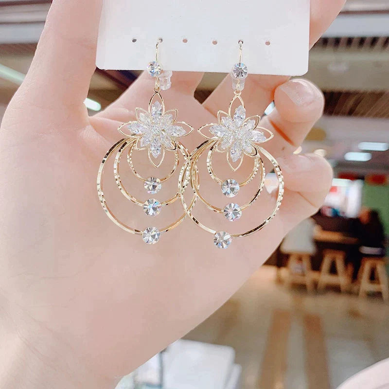 Goldene Ohrringe mit Kristallen, Blumenmotiv, hängend, elegant, Schmuck für Damen.