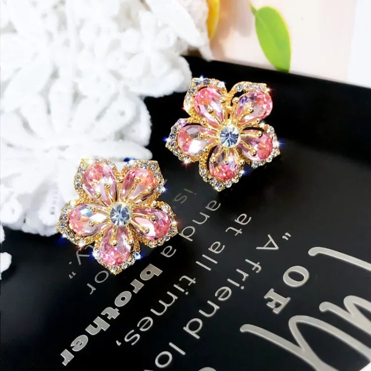 Goldene Ohrringe mit rosa Kristallblumen, eleganter Schmuck, modisches Accessoire.