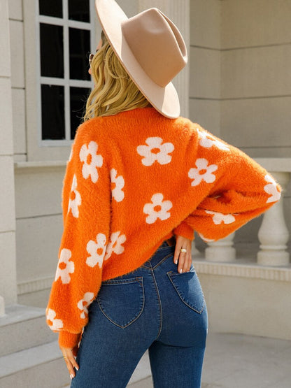 Frau in orangefarbenem Blumenpullover und Hut, Rückansicht, modisch, Herbstmode, draußen.