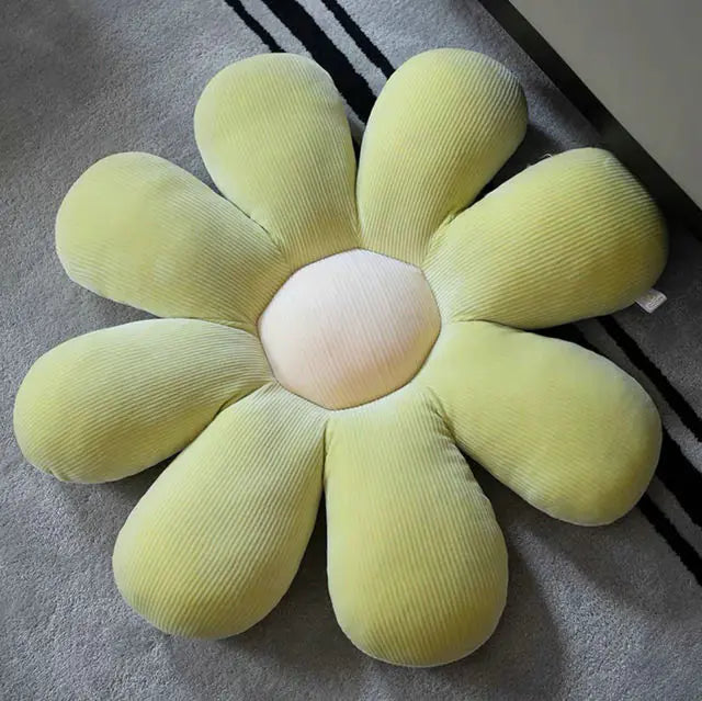 Gelbes Blumenkissen aus Cordstoff auf grauem Teppich, dekoratives Wohnaccessoire.