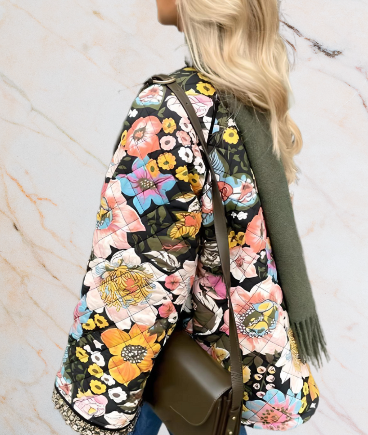 Frau mit bunter Blumenjacke, olivgrüner Schal, braune Umhängetasche, Marmorhintergrund.