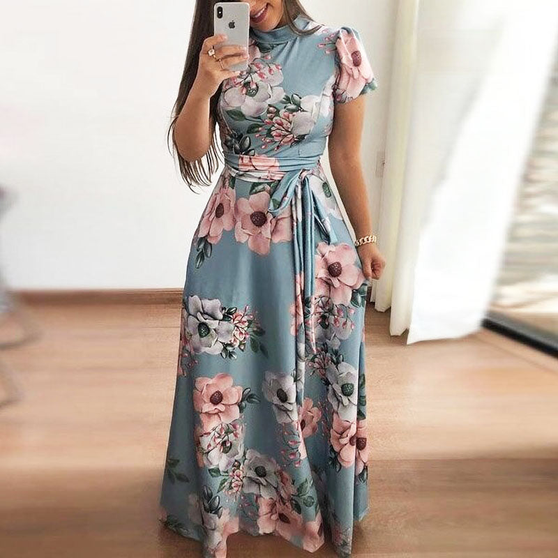 Frau in langem, blauem Blumenkleid mit Gürtel, florales Muster, elegantes Sommeroutfit.