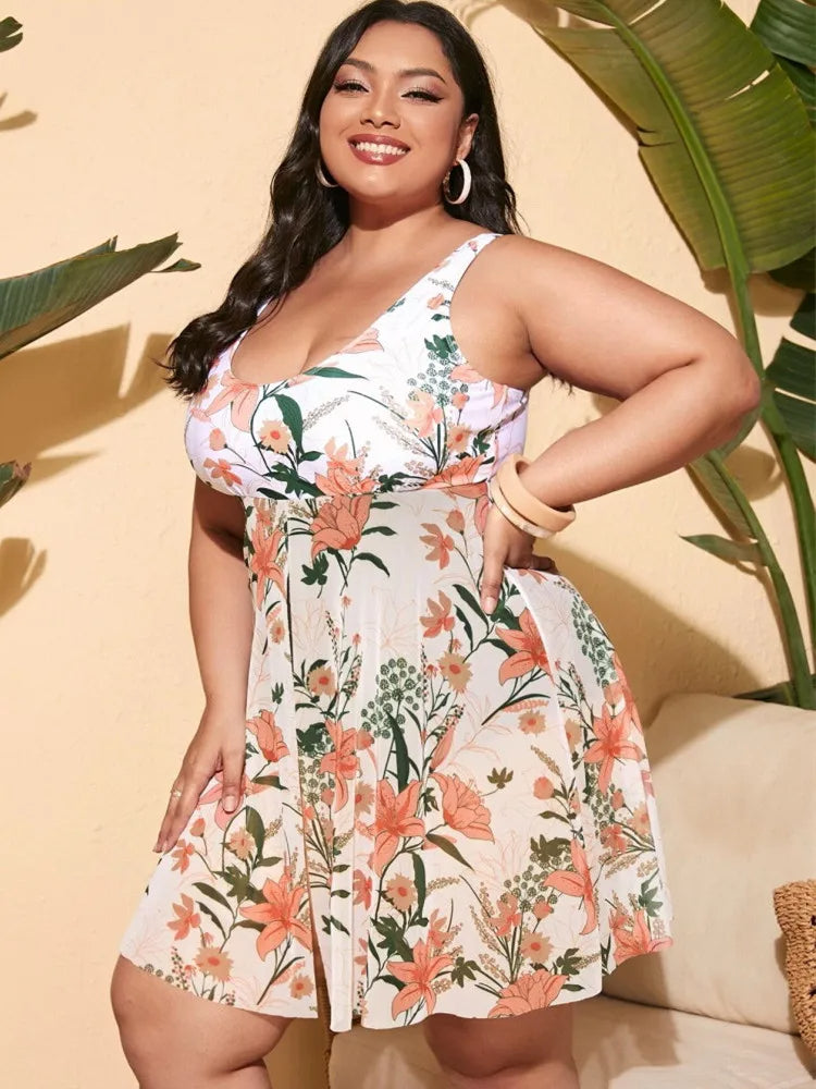 Frau in geblümtem Sommerkleid, Plus-Size, weiß-orange, tropisches Design, lächelnd, drinnen.