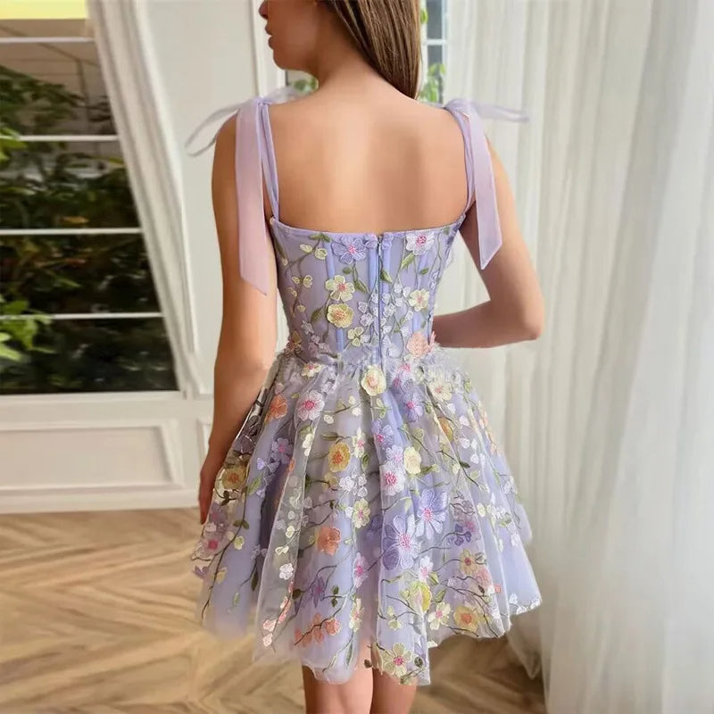 Lila Blumen-Sommerkleid, ärmellos, mit Schleifen, aus Tüll, ideal für festliche Anlässe.
