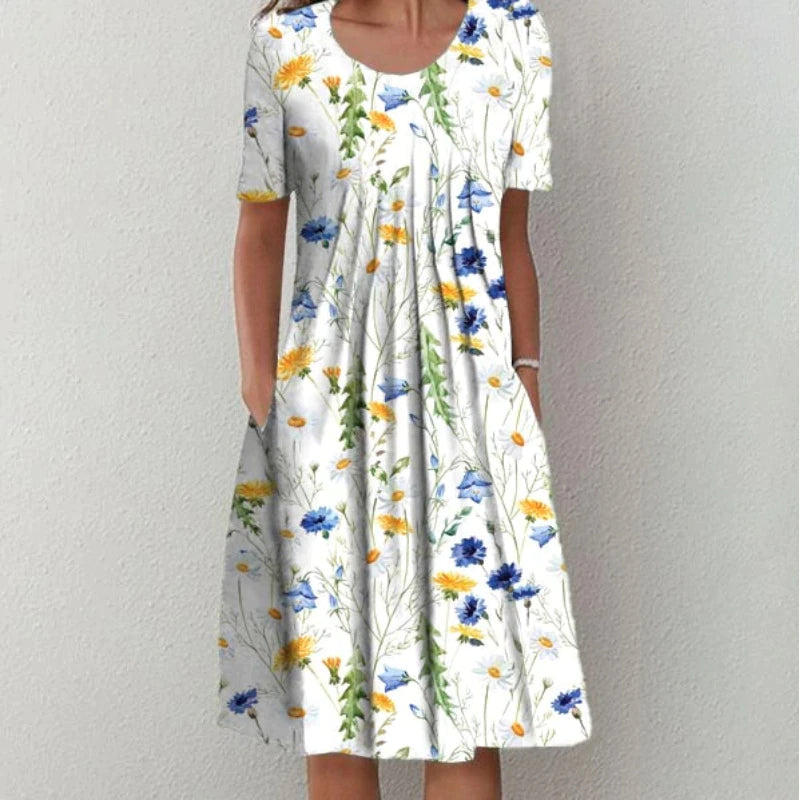 Frau in weißem Blumenkleid mit blauen und gelben Blumen, Sommermode, knielang, kurzärmelig.