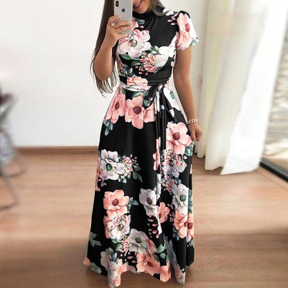 Frau in langem, schwarzem Blumenkleid mit rosa und weißen Blumenmuster, Sommermode.