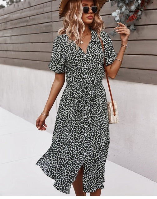 Frau in geblümtem Sommerkleid, Strohhut, Sonnenbrille, Handtasche, lässiger Look.