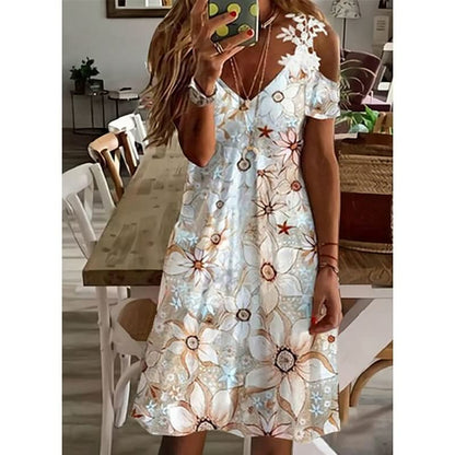 Frau in weißem Sommerkleid mit Blumenmuster, schulterfrei, stehend in modernem Esszimmer.