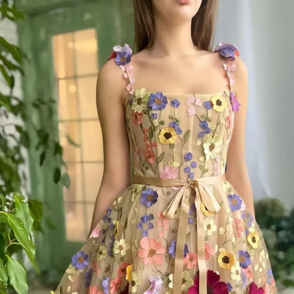 Frau in einem floralen, ärmellosen Kleid mit bunten Blumenstickereien, Sommermode, elegant.