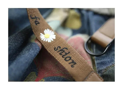 Brauner Stoffgürtel mit Gänseblümchen und "fashion"-Stickerei, Nahaufnahme.