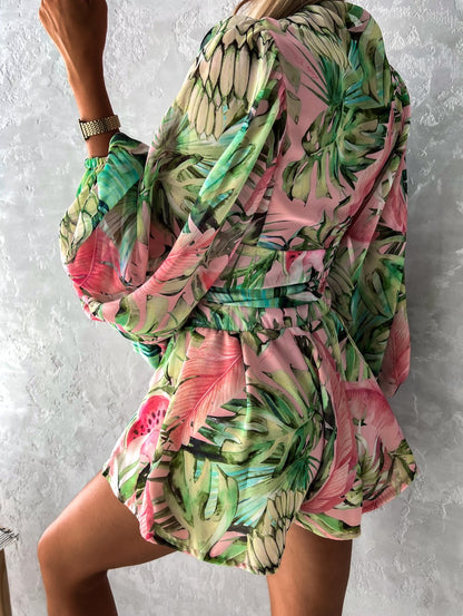 Frau in grün-rosa tropischem Kleid, langärmelig, Sommermode, florales Muster.