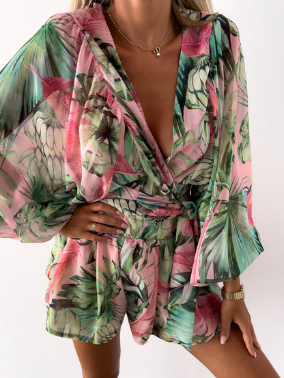 Frau in grün-rosa geblümtem Sommerkleid, V-Ausschnitt, lange Ärmel, tropisches Muster.