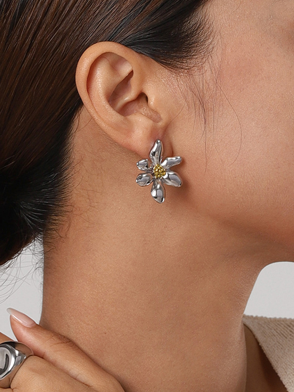 Frau mit silbernen Blumenohrringen, eleganter Schmuck, Nahaufnahme, modisches Accessoire.