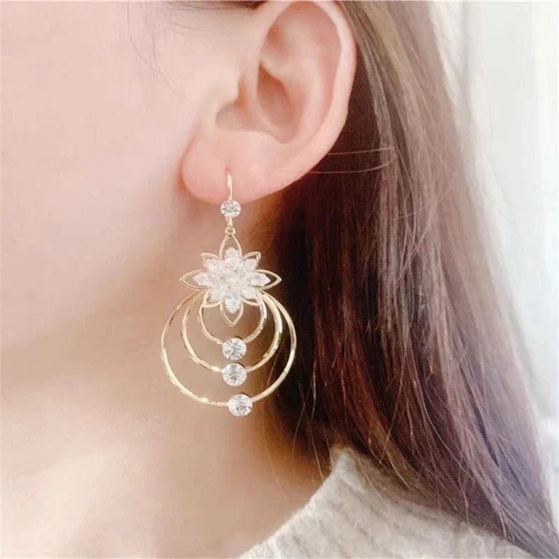 Goldene Ohrringe mit Blumenmotiv und Kristallen, eleganter Schmuck für Damen.