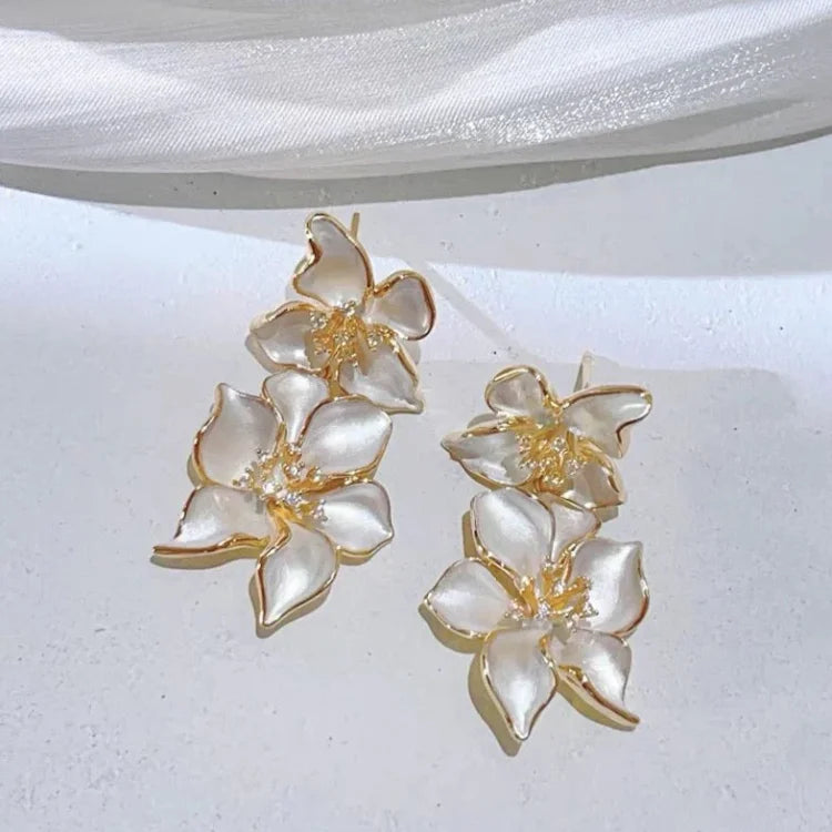Goldene Ohrringe mit weißen Blüten, eleganter Schmuck, modische Accessoires für Damen.