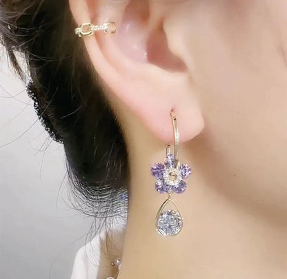 Frau mit lila Blumenohrring und Ohrstecker, eleganter Schmuck, Nahaufnahme.