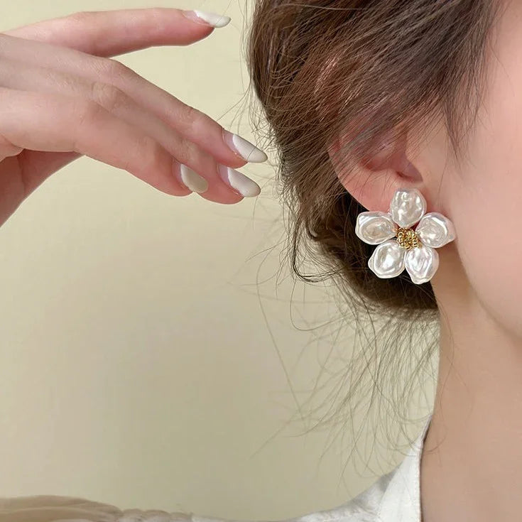 Frau mit großen, weißen Blumenohrringen aus Perlen, Nahaufnahme, eleganter Schmuck.