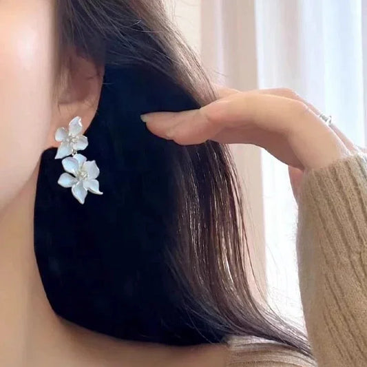 Frau mit weißen Blumenohrringen, eleganter Schmuck, Nahaufnahme, modisches Accessoire.
