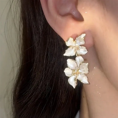 Ohrringe mit weißen Blumen, goldene Details, eleganter Schmuck, modisches Accessoire, Damenmode.