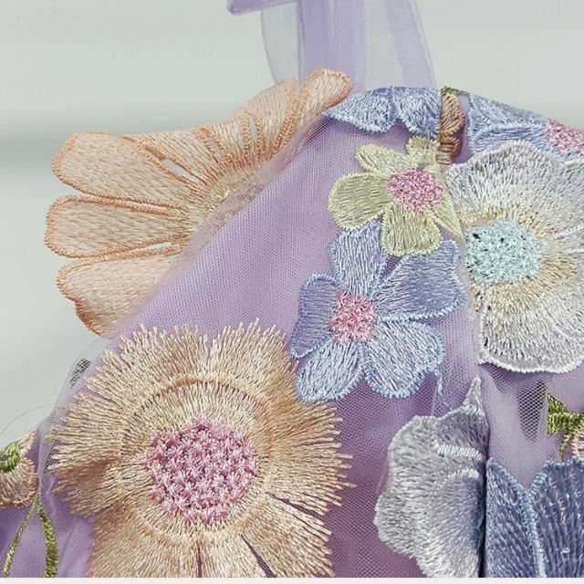 Lila Stoff mit floraler Stickerei, pastellfarben, Blumenmuster, Textildesign, Nahaufnahme.