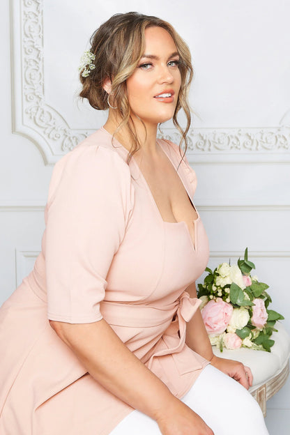 Frau in rosa Kleid mit Blumenstrauß, elegante Frisur, Porträtfotografie, Hochzeitsmode.