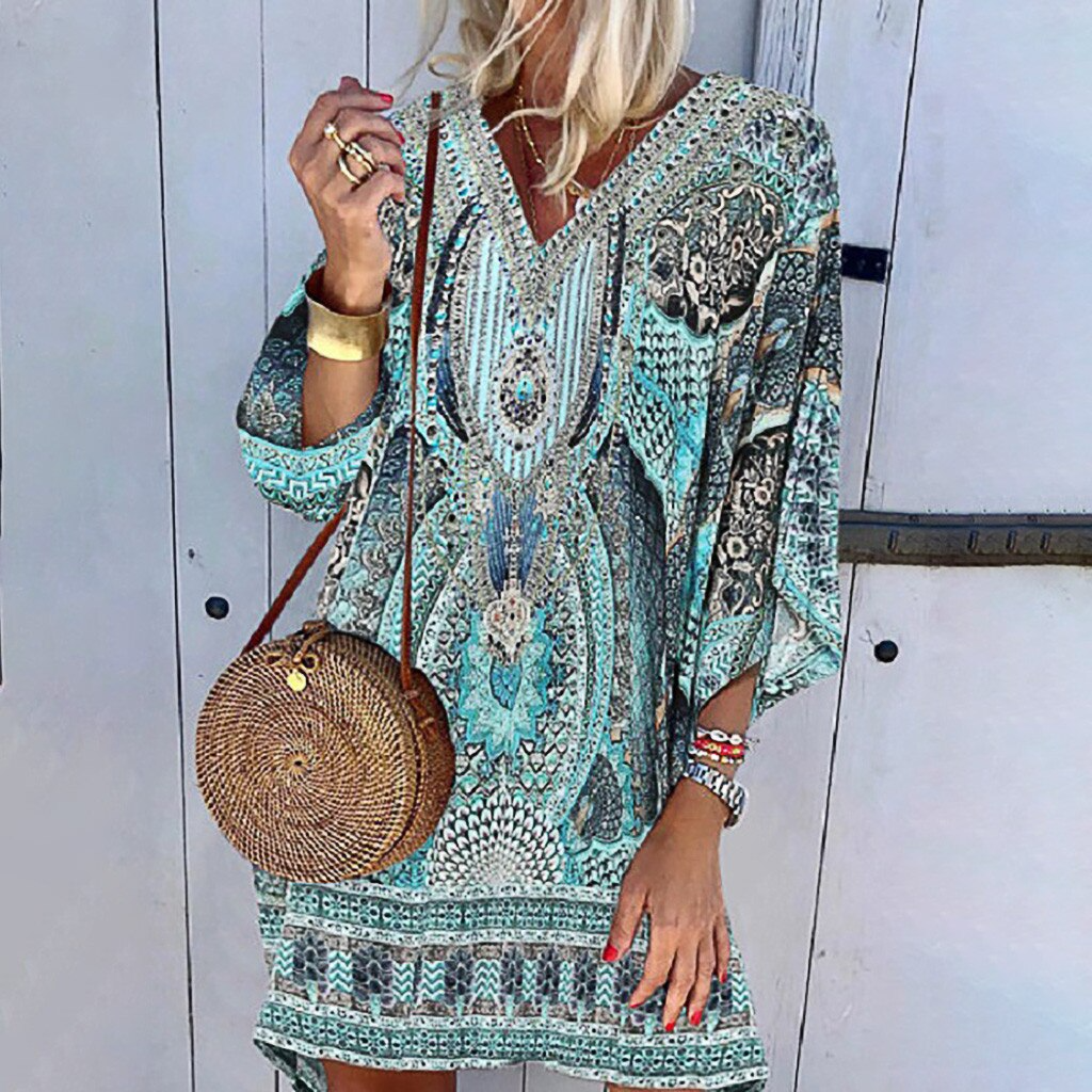 Frau in boho Print Minikleid, blau-grün, mit runder Strohtasche, lässig, lange Ärmel.