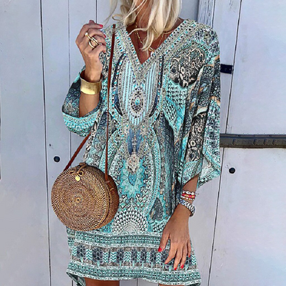 Frau in boho Print Minikleid, blau-grün, mit runder Strohtasche, lässig, lange Ärmel.