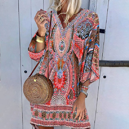 Frau in bunter Boho-Minikleid mit langen Ärmeln, runde Strohtasche, modisch, lässig.