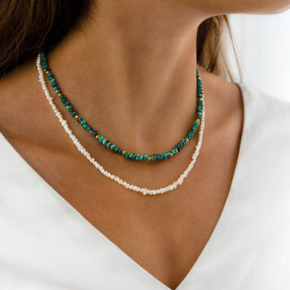 Frau trägt türkis-weiße Halskette, Sommermode, handgefertigter Schmuck, elegantes Design.