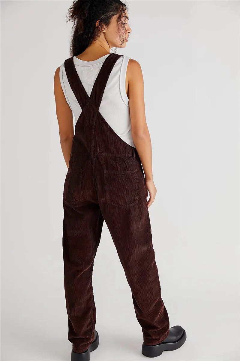 Frau in brauner Cord-Latzhose, weißem Tanktop, schwarze Schuhe, Rückansicht, modisch, lässig.