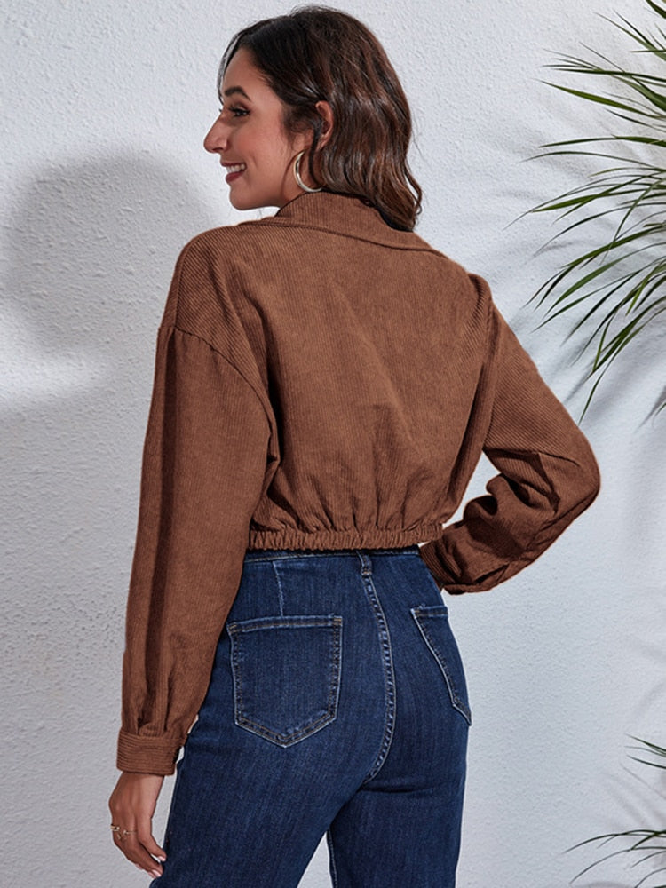 Frau in brauner Cordjacke und blauer Jeans, lässige Mode, Herbstoutfit, Rückansicht.
