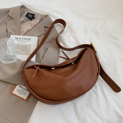 Braune Leder-Umhängetasche auf beigem Blazer, stilvoll, modern, Damenmode Accessoire.