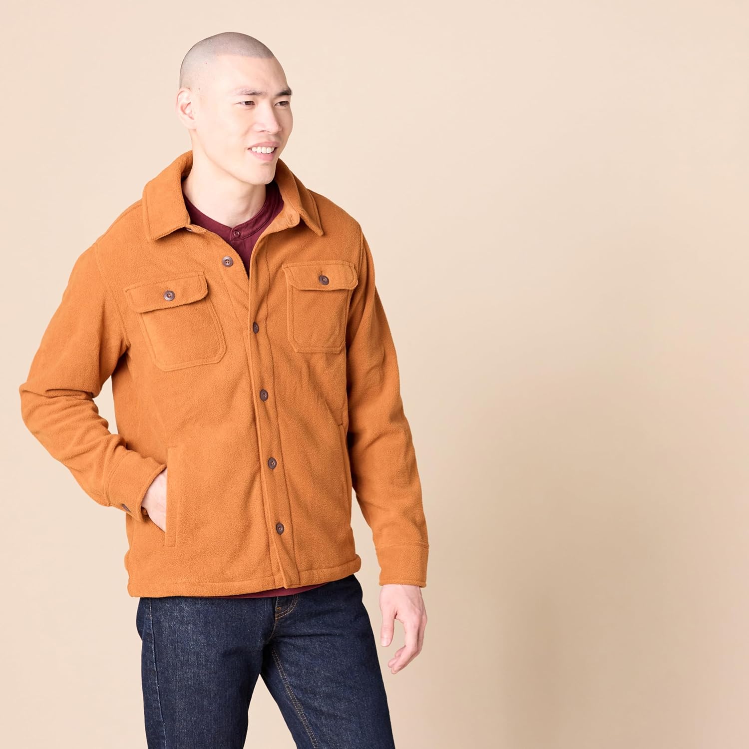 Mann in brauner Wolljacke mit Knöpfen, zwei Brusttaschen, lässiger Stil, beige Hintergrund.