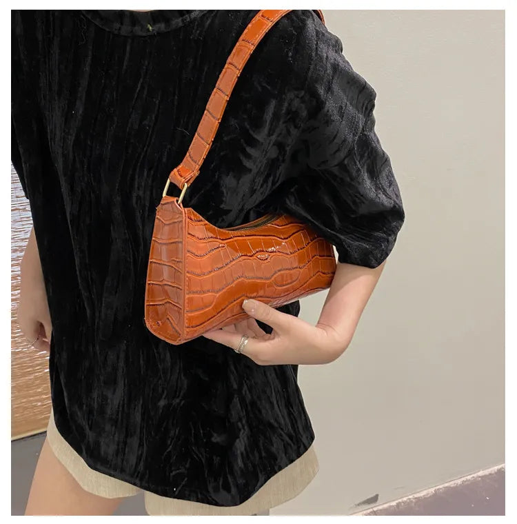 Frau mit brauner Krokodilleder-Handtasche, schwarzem Samtoberteil, modisch, elegant.