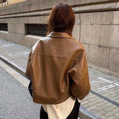 Frau in brauner Lederjacke auf Straße, modisch, urban, Herbstmode, Rückansicht.