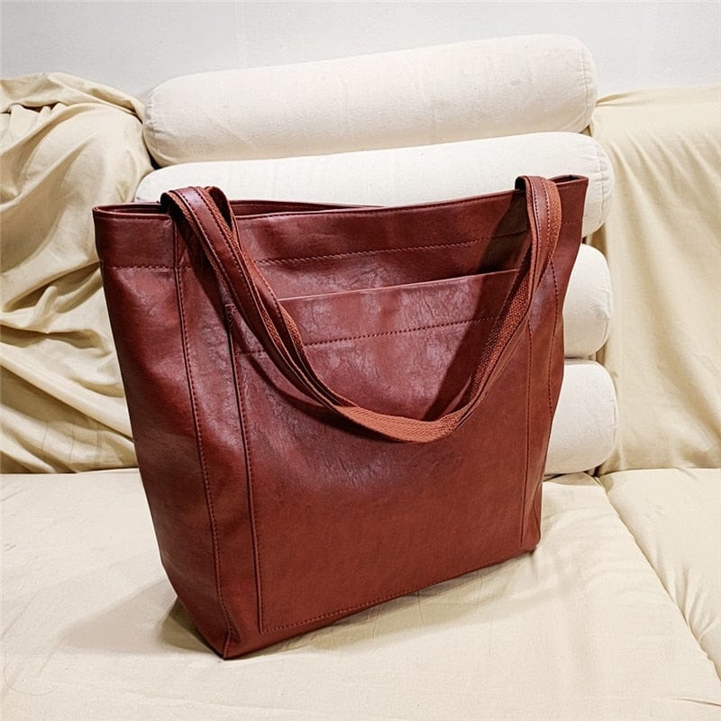 Braune Ledertasche auf beigem Sofa, langlebig, modisch, ideal für Alltag und Reisen.