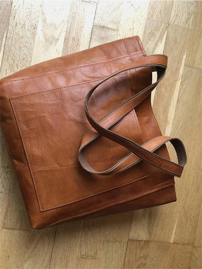 Braune Ledertasche auf Holzboden, langlebig, modisch, umweltfreundlich, hochwertige Tragetasche.