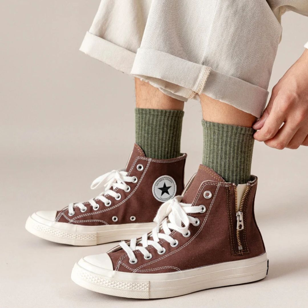 Braune High-Top-Sneaker mit Reißverschluss, grüne Socken, weiße Schnürsenkel, lässiger Stil.