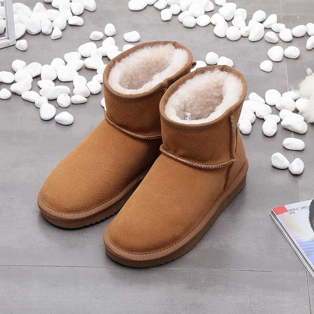 Braune Damen-Winterstiefel aus Wildleder mit Lammfellfutter auf grauem Boden.