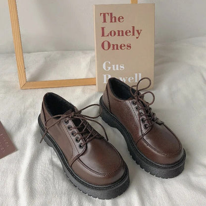 Braune Leder-Derby-Schuhe mit dicker Sohle vor Buch "The Lonely Ones" auf weißem Hintergrund.